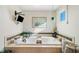 Relaxing soaking tub featuring plants, a tiled surround, and natural light at 487 Carmichael Cir, Canton, GA 30115