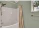 White tiled bathtub and shower featuring brushed nickel fixtures and a glass paneled window at 4112 Willow Sw Walk, Lilburn, GA 30047