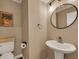 Neutral half bathroom with a stylish round mirror, pedestal sink, and modern lighting at 4112 Willow Sw Walk, Lilburn, GA 30047