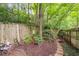 A cozy fenced backyard featuring a small deck and stone pathway amongst mature trees and greenery at 1346 Peter Haughton Nw Way, Atlanta, GA 30318