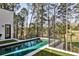 A modern pool is surrounded by lush landscaping, with views of mature trees, and a metal railing, offering a serene backyard retreat at 1572 Clifton Rdg, Atlanta, GA 30307