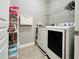 Well-organized laundry room featuring a washer, dryer, storage shelves, and tiled floor at 4071 Woodward Walk Ln, Suwanee, GA 30024
