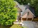 Aerial view of a brick home showcasing roof, two-car garage, landscaped yard, and surrounding greenery at 5105 Tynewick Ne Trce, Roswell, GA 30075