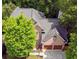 Aerial view of a brick home with a dark roof, surrounded by lush green trees at 5105 Tynewick Ne Trce, Roswell, GA 30075
