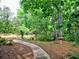 Lush backyard with stone pathway leading to a bird bath, surrounded by mature trees and greenery at 5105 Tynewick Ne Trce, Roswell, GA 30075