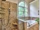 Elegant bathroom featuring a glass shower and luxurious soaking tub with tile surround and window at 5105 Tynewick Ne Trce, Roswell, GA 30075