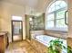 Bathroom featuring tiled floors, glass shower, and soaking tub with arched window at 5105 Tynewick Ne Trce, Roswell, GA 30075