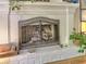 Close up of a beautiful white brick fireplace with decorative details and a metal fire screen at 5105 Tynewick Ne Trce, Roswell, GA 30075