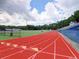 Bright red running track with white lane markings leading to a sports field and stadium seating at 5105 Tynewick Ne Trce, Roswell, GA 30075