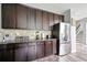 Well-lit kitchen features stainless steel refrigerator, dark wood cabinetry, and granite countertops at 7698 Hansel Ln, Lithonia, GA 30058