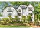 Gorgeous white home featuring a manicured lawn, mature landscaping and unique wrought iron fencing detail at 900 Edgewater Nw Dr, Atlanta, GA 30328