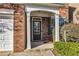 Close up of front entrance featuring storm door, white pillars, brick facade and manicured garden at 1538 Park Grove Dr, Lawrenceville, GA 30046