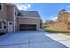 Rear exterior view showing a two-car garage with a concrete driveway and fenced yard at 20 Daniel Crk, Sugar Hill, GA 30518