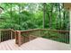 Wood deck with railing offers an outdoor space surrounded by a lush, green treeline at 1855 Vintage Dr, Snellville, GA 30078