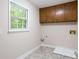 Bright laundry room featuring overhead cabinets, a window, connections for a washer and dryer, and tile flooring at 1855 Vintage Dr, Snellville, GA 30078