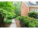 A winding walkway meanders through a lush side yard filled with mature trees and plants at 1855 Vintage Dr, Snellville, GA 30078