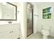 Bathroom with a shower featuring a glass door, vanity with a mirror and a window at 1864 Gloucester Ct, Snellville, GA 30078