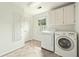 Well lit laundry room with tile floors, washer, dryer and storage cabinets at 1864 Gloucester Ct, Snellville, GA 30078