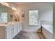 Bright bathroom features a double sink vanity and bathtub beneath a large window at 5601 Savannah River Rd, Atlanta, GA 30349