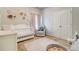 Bedroom with a white crib, rocker, and floral wall decor, offering a tranquil and charming setting at 5601 Savannah River Rd, Atlanta, GA 30349