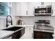 Close up of the kitchen features stainless steel appliances, black kitchen sink, white cabinets, and white backsplash at 904 Fairburn Nw Pl, Atlanta, GA 30331