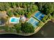Aerial view of pool and tennis courts near lake, surrounded by lush greenery and mature trees at 448 Teal Ct, Roswell, GA 30076