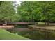 Picturesque wooden bridge over a calm stream, framed by green foliage and stone embankments at 448 Teal Ct, Roswell, GA 30076