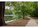 Scenic view of a paved walking path along the lake, surrounded by lush green trees at 448 Teal Ct, Roswell, GA 30076