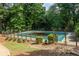 View of the community pool, surrounded by mature trees and a decorative stone border at 448 Teal Ct, Roswell, GA 30076