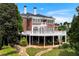 Backyard showcases a patio under a deck, lush landscaping, and stone walkway leading through a beautiful green lawn at 5070 Riverlake Dr, Peachtree Corners, GA 30097