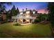 Stunning backyard with lush lawn, large patio, and a beautiful two-story brick home with multiple decks at dusk at 5070 Riverlake Dr, Peachtree Corners, GA 30097