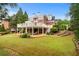 Stunning backyard with lush lawn, large patio, and a beautiful two-story brick home with multiple decks at 5070 Riverlake Dr, Peachtree Corners, GA 30097