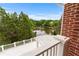 A lovely balcony with white railing overlooking a peaceful lake surrounded by lush trees and greenery at 5070 Riverlake Dr, Peachtree Corners, GA 30097