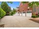 Spacious driveway leading to a three-car garage, surrounded by beautiful landscaping and a brick home at 5070 Riverlake Dr, Peachtree Corners, GA 30097