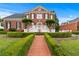 Elegant brick home with a manicured lawn, trimmed hedges, and a brick walkway leading to the entrance at 5070 Riverlake Dr, Peachtree Corners, GA 30097