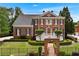Stunning two-story brick home featuring a manicured lawn and an inviting arched entryway with black metal gate at 5070 Riverlake Dr, Peachtree Corners, GA 30097