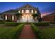 Elegant brick home featuring manicured lawn, trimmed hedges, and a brick walkway leading to entrance, lit by outdoor lights at 5070 Riverlake Dr, Peachtree Corners, GA 30097