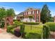 Beautiful two-story brick home with manicured landscaping, a wrought iron fence and a charming brick archway at 5070 Riverlake Dr, Peachtree Corners, GA 30097
