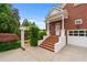 Exterior view showcasing a brick home with a white pergola and manicured landscaping, plus a three-car garage at 5070 Riverlake Dr, Peachtree Corners, GA 30097