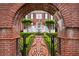 Elegant front entrance framed by a brick archway and ornate iron gate, showcasing the home's manicured front yard at 5070 Riverlake Dr, Peachtree Corners, GA 30097