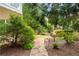 Landscaped backyard with stone path leading through lush greenery; decorative bird bath and mature trees at 5070 Riverlake Dr, Peachtree Corners, GA 30097