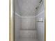 A glass enclosed shower featuring grey ceramic tiles with a built-in bench and brass shower fixtures at 5070 Riverlake Dr, Peachtree Corners, GA 30097