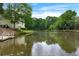 Scenic view of a tranquil lake with reflections, surrounded by lush trees and elegant homes at 5070 Riverlake Dr, Peachtree Corners, GA 30097