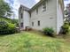 Side view of the backyard featuring lush grass, mature trees, and utility access points for functionality at 3419 White Sands Way, Suwanee, GA 30214
