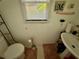 A compact bathroom featuring a toilet, sink, and a small window for natural light and ventilation at 3419 White Sands Way, Suwanee, GA 30214