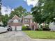 Traditional brick home with a three-car garage, landscaped front yard, and a well-manicured lawn at 3419 White Sands Way, Suwanee, GA 30214