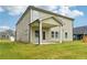 Backyard showcasing green lawn, neutral siding, and covered porch with white pillars at 6905 Winchester Pl, Fairburn, GA 30213