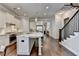 Bright open kitchen, featuring an island, stainless appliances, white cabinets, hardwood floors, and a staircase at 919 Olmsted Ln, Johns Creek, GA 30097