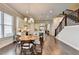 Bright open kitchen and dining area featuring an island, stainless appliances, white cabinets, hardwood floors, and a staircase at 919 Olmsted Ln, Johns Creek, GA 30097