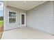An outdoor covered patio featuring light grey siding, white trim, a single door, and a window for natural lighting at 6908 Winchester Pl, Fairburn, GA 30213
